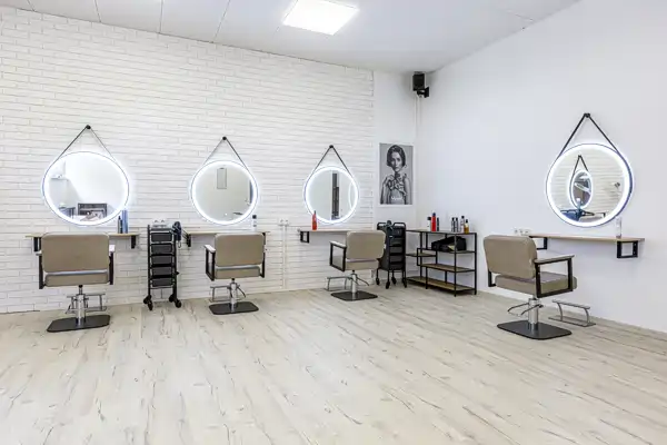 Foto der Frauenabteilung von Friseur Salim, mit Stühlen, beleuchteten Spiegeln und Arbeitsbereichen auf einem Holzboden.